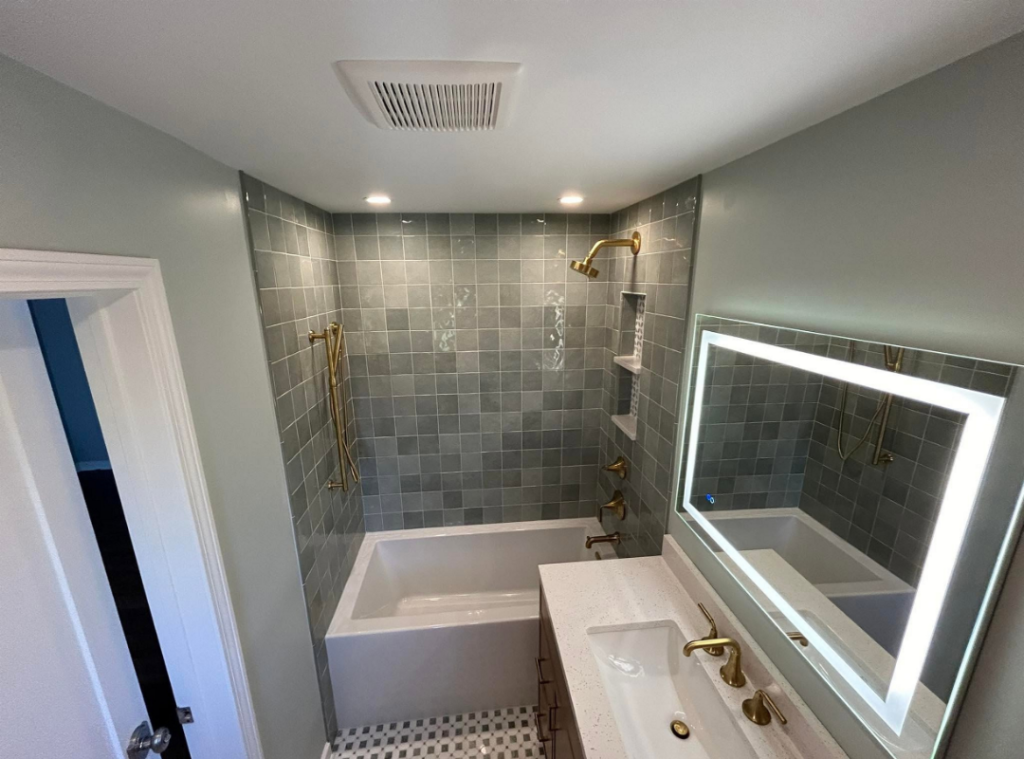 Newly renovated bathroom with gray tile, new floors, new vanity and tub