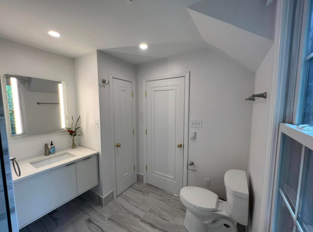 A newly renovated bathroom in Pittsburgh with white vanity, new tub and tile, new floors, and new fixtures.